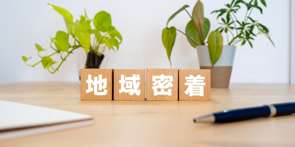 「地域密着」の木製ブロックと観葉植物のテーブルシーン