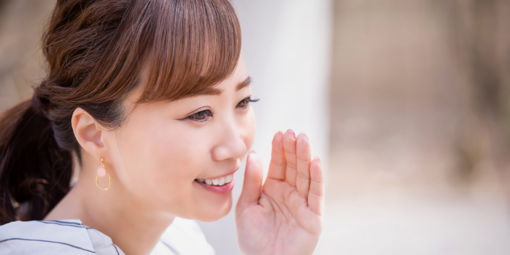 口元に手を添えて話す女性の横顔