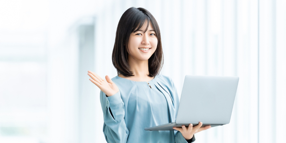 ノートパソコンを手に笑顔で案内する女性